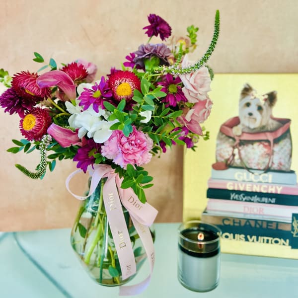 Mixed pink and purple bouquet in a glass vase with a ribbon
