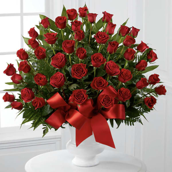 Large bouquet of red roses in a white vase with a red ribbon