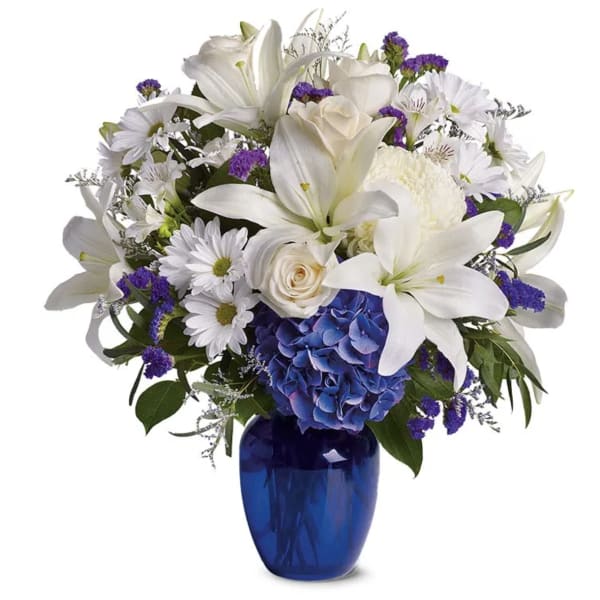 White lilies and daisies with purple accents in a blue vase
