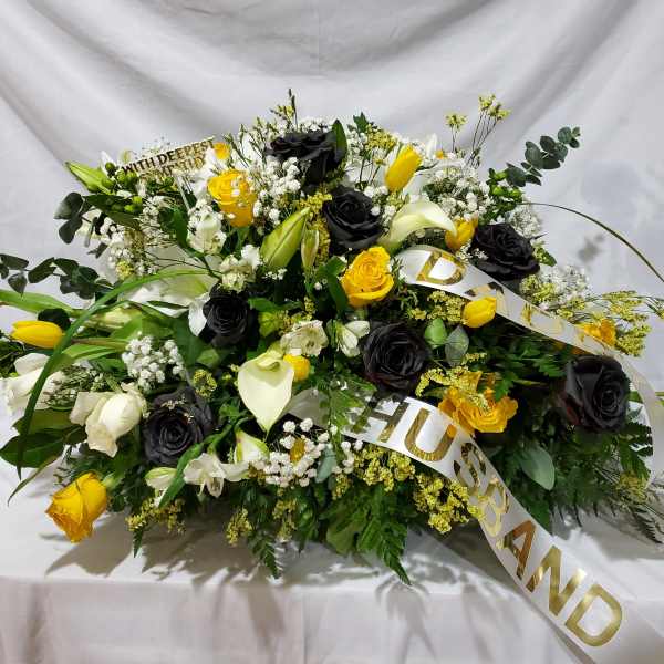 Large floral spray with black and yellow roses and white lilies