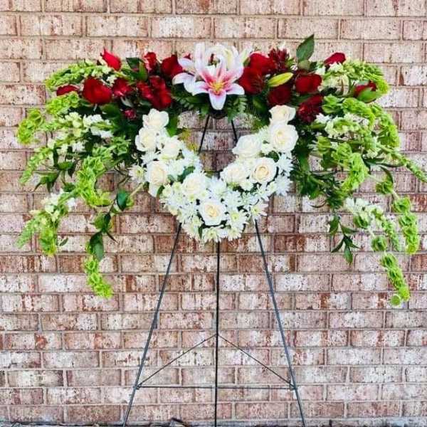 Standing floral wreath with red and white flowers on a metal easel