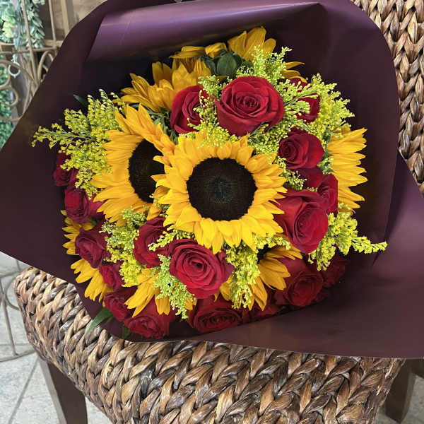 Bouquet of red roses and yellow sunflowers wrapped in dark paper