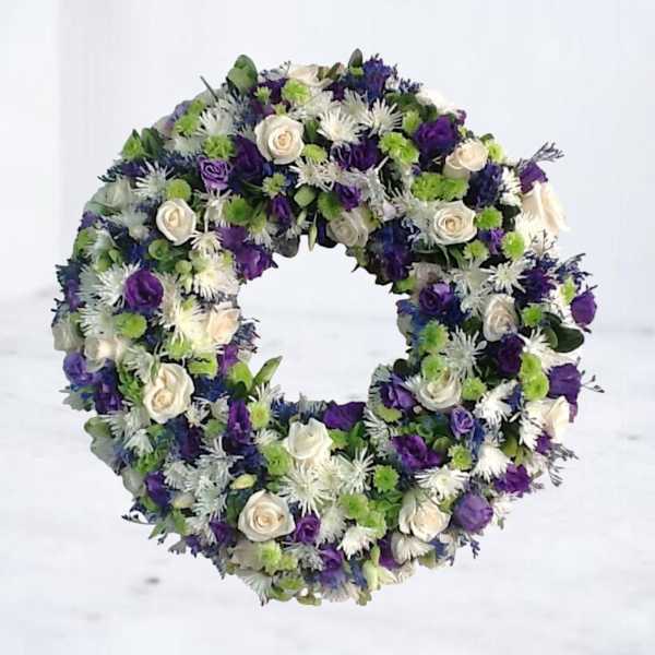 Circular wreath of white, purple, and green flowers
