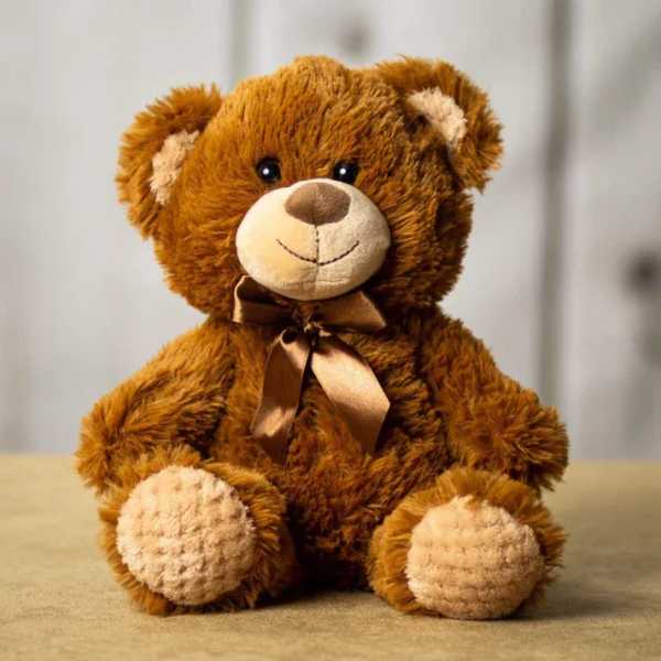 Brown teddy bear with a satin ribbon sitting on a neutral surface