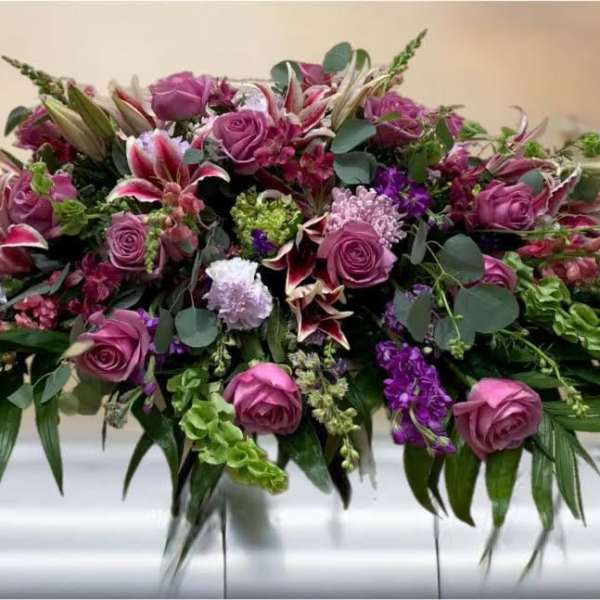 Large purple and pink floral casket spray with roses and lilies