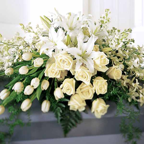 White floral casket spray with lilies, roses, and tulips