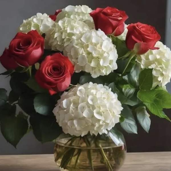 Red roses and white hydrangeas in a round glass vase