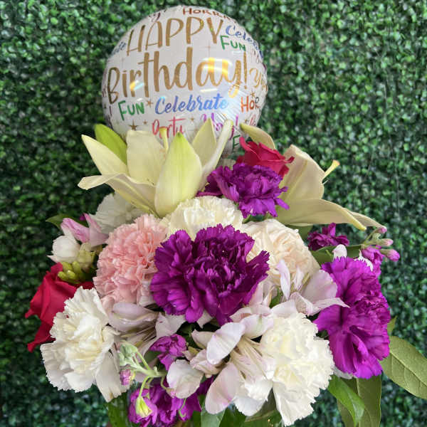 Birthday balloon above a mixed bouquet in a glass vase