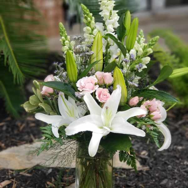 White lilies and pink roses arranged in a glass vase