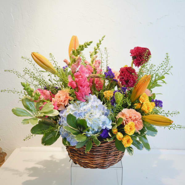 Mixed bouquet in a wicker basket with lilies, hydrangea, roses, and carnations