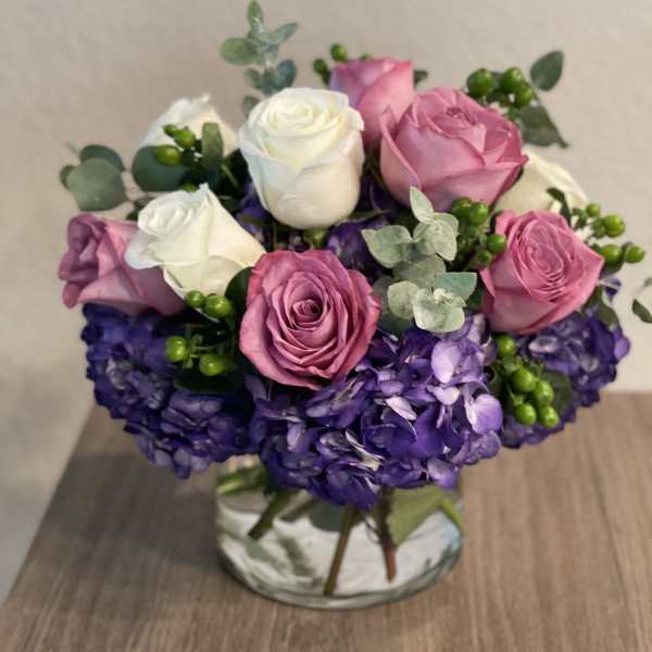 Bouquet of pink and white roses with purple hydrangeas in a vase