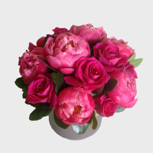 Pink peonies and roses arranged in a white vase