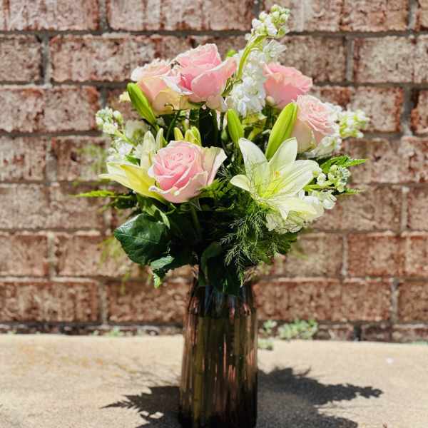 Pink roses and white lilies in a dark glass vase