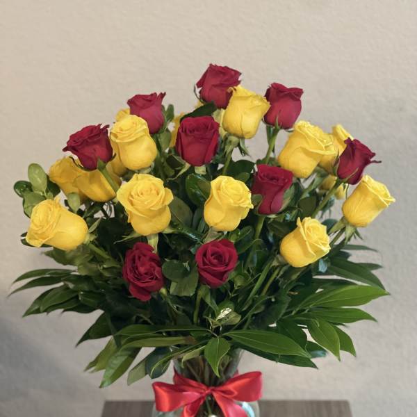 Bouquet of red and yellow roses in a glass vase with a red ribbon