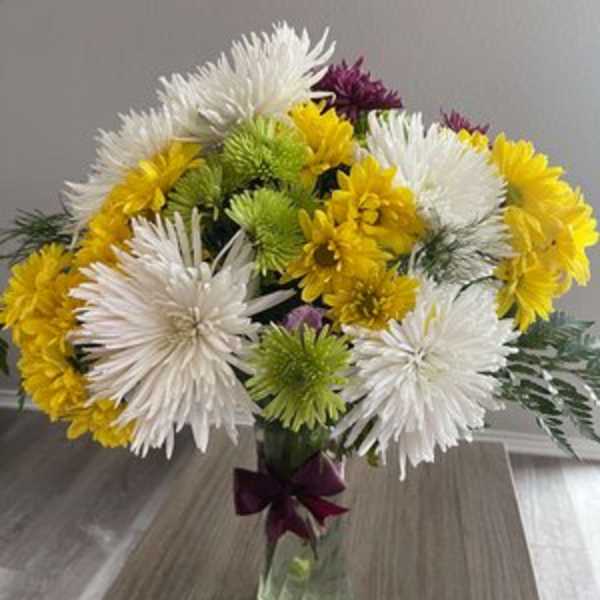 Bouquet of white, yellow, and green chrysanthemums in a glass vase