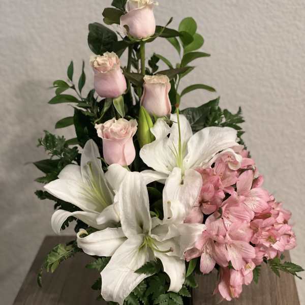 Pink roses and white lilies arranged in a black vase with pink alstroemeria