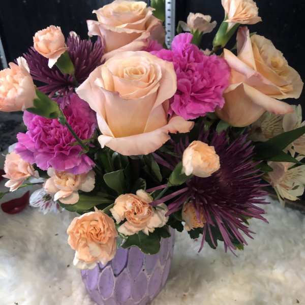 Peach roses and pink carnations in a lavender vase
