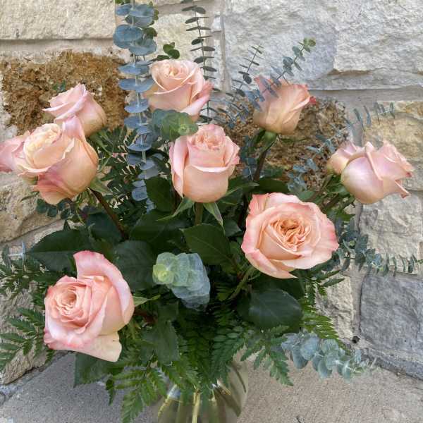 Pink roses in a glass vase with eucalyptus