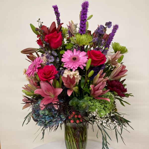 Mixed pink, purple, and green flowers arranged in a glass vase