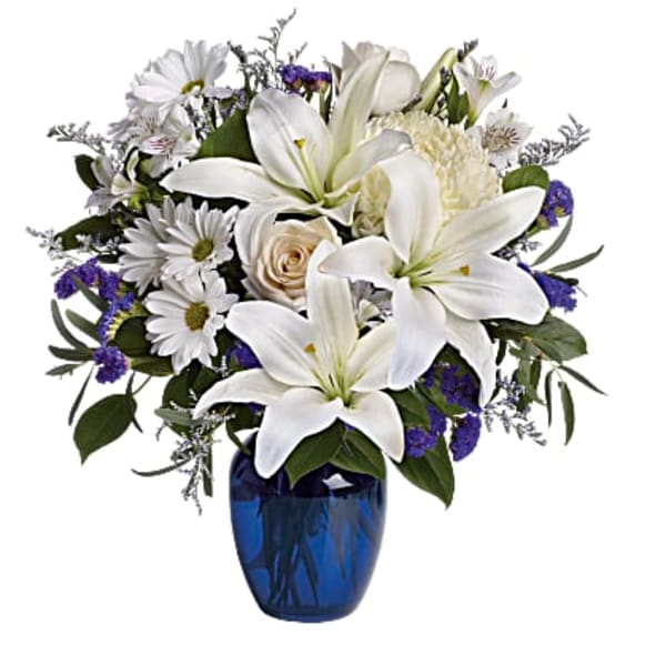 White lilies and daisies in a blue glass vase