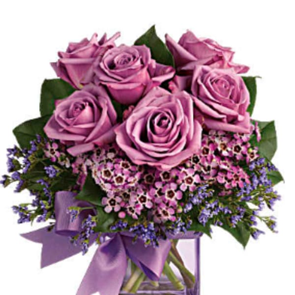 Pink roses in a clear glass vase with a purple ribbon