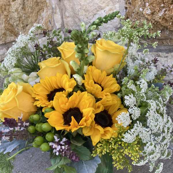 Bouquet of yellow roses and sunflowers in a green vase