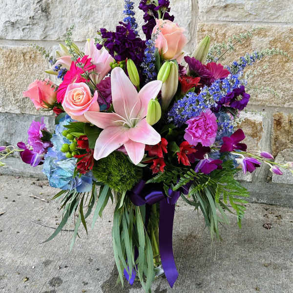Colorful bouquet with pink lilies, roses, and purple flowers in a vase