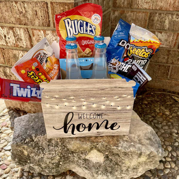 Snack basket with chips, candy, and bottled drinks in a welcome home box