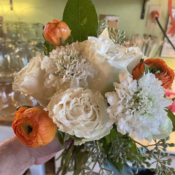 Handheld bouquet of white roses, white blooms, and orange ranunculus