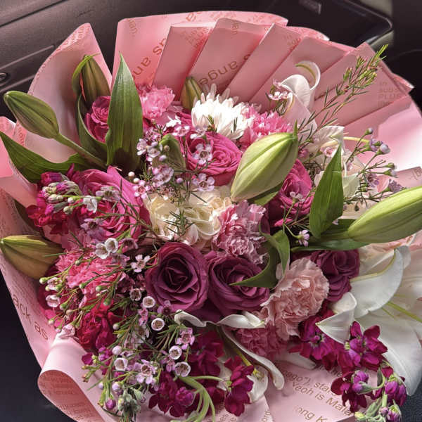 Pink and white bouquet with roses, lilies, and carnations wrapped in pink paper