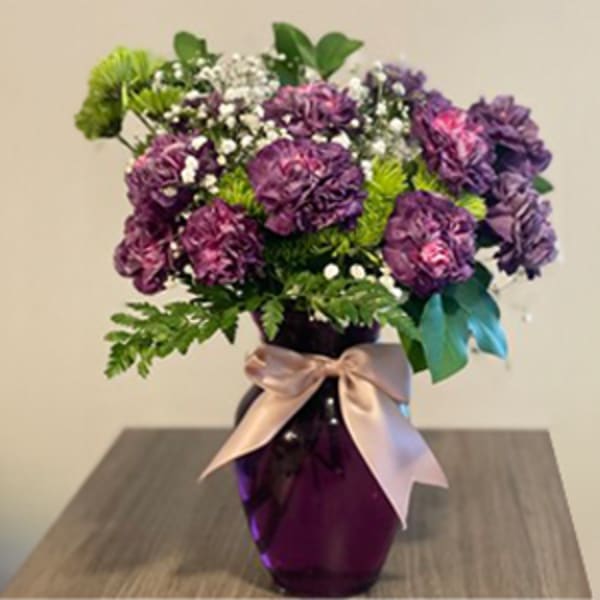 Purple bouquet in a dark vase with a satin ribbon