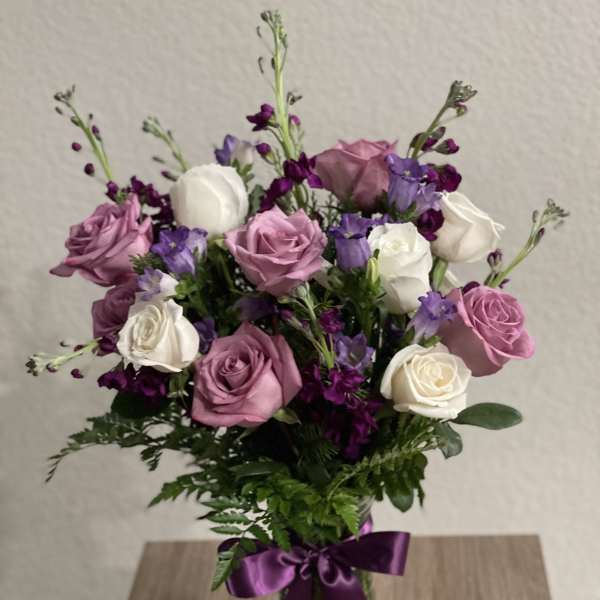 Pink and white roses with purple flowers in a glass vase