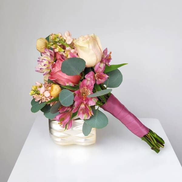 Pink and cream bouquet in a white vase with a magenta handle wrap