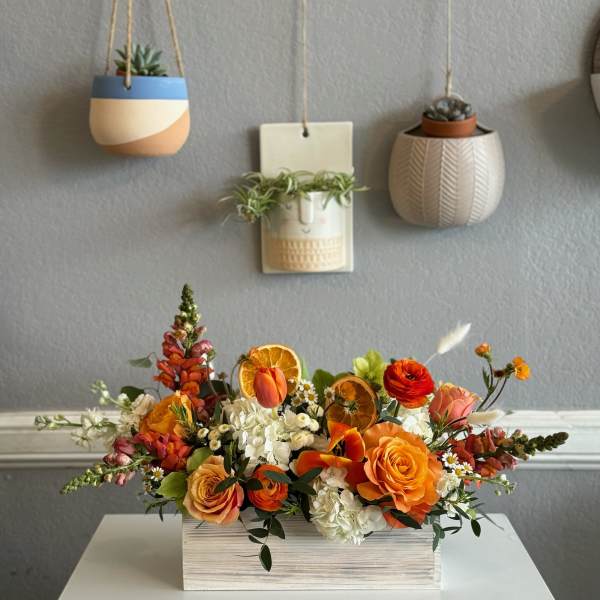 Orange and white floral arrangement in a rectangular wooden box