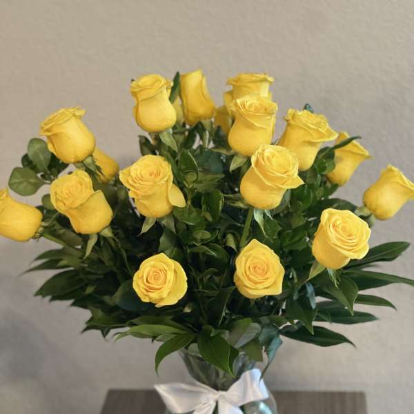 Yellow roses in a glass vase tied with a white ribbon