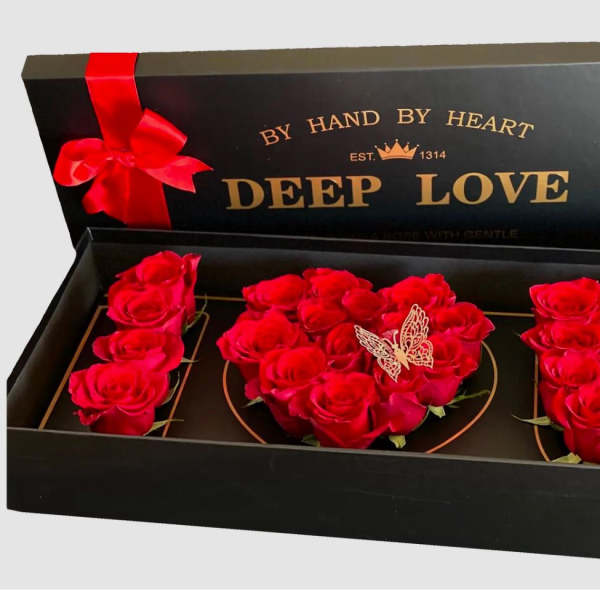 Red roses arranged in a black gift box with a ribbon and butterfly decoration