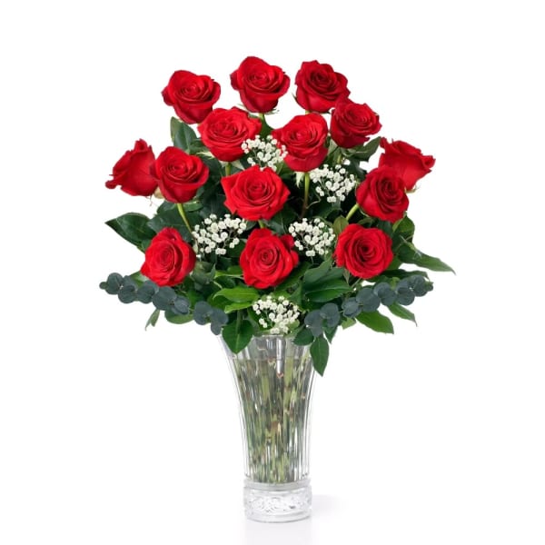 Red roses arranged in a clear glass vase with white filler flowers