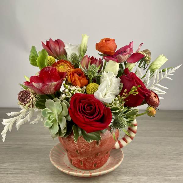 Colorful mixed flower arrangement in a red teacup vase