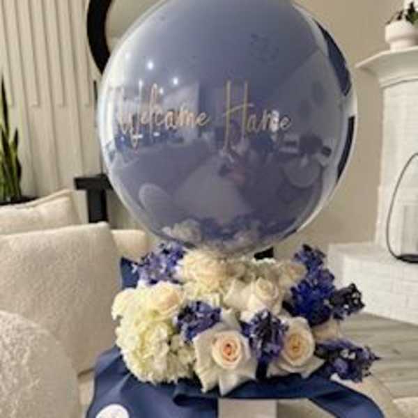 Blue balloon above white and blue roses in a gift arrangement