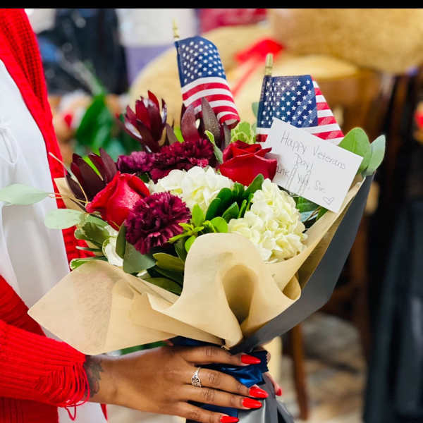 Bouquet of red roses, white hydrangeas, and burgundy flowers with small U.S. flags