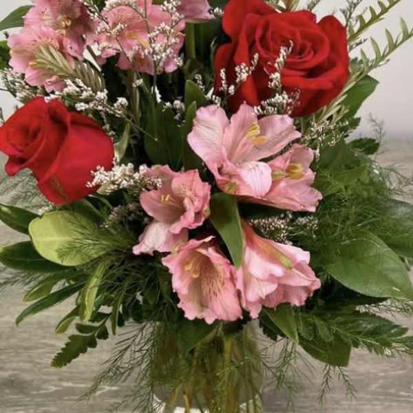 Bouquet of red roses and pink flowers in a clear glass vase