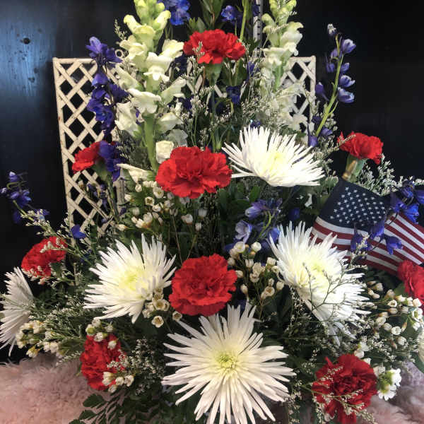 Red carnations and white spider mums in a basket with small flags