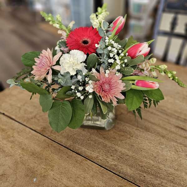 Mixed pink and white flowers arranged in a clear glass vase