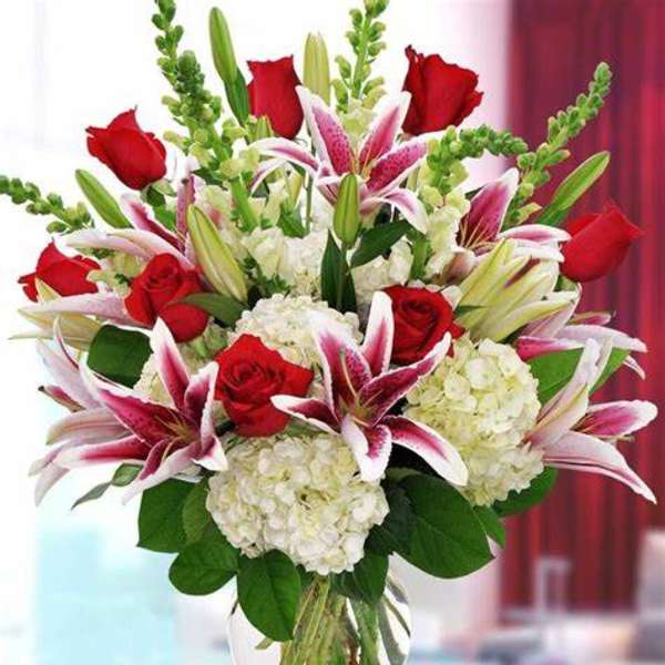 Bouquet of red roses, white hydrangeas, and pink lilies in a glass vase