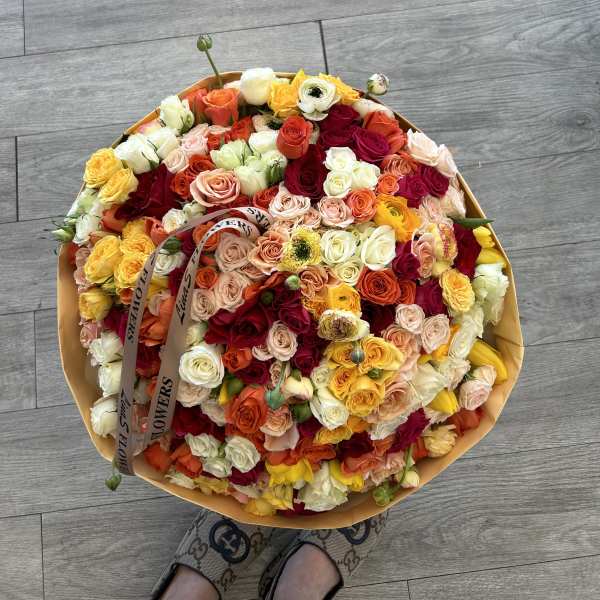 Large round bouquet of multicolored roses wrapped in tan paper