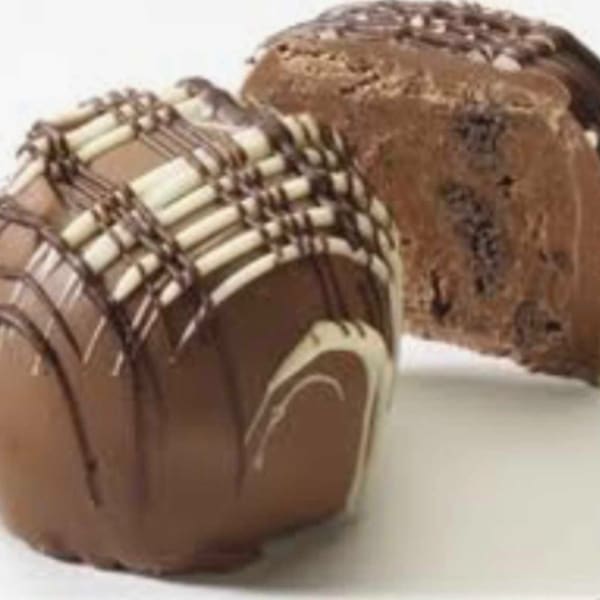 Two chocolate-covered loaves with white drizzle on a white surface