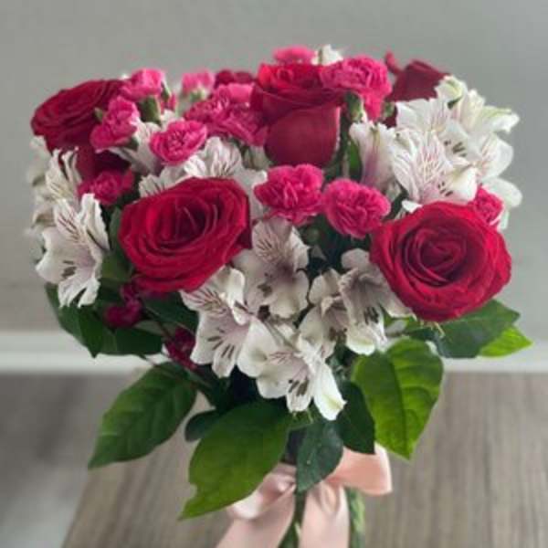 Bouquet of pink roses and white alstroemeria in a glass vase