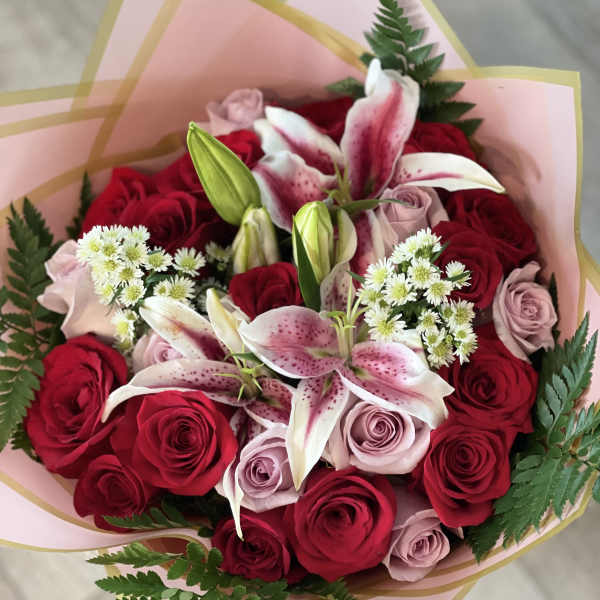 Bouquet of red and blush roses with pink lilies and white filler flowers