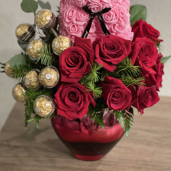 Pink teddy bear made of roses with red roses and chocolates in a vase
