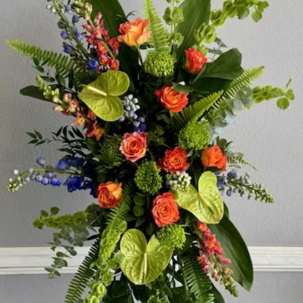 Tall floral spray with orange roses and bright green tropical accents